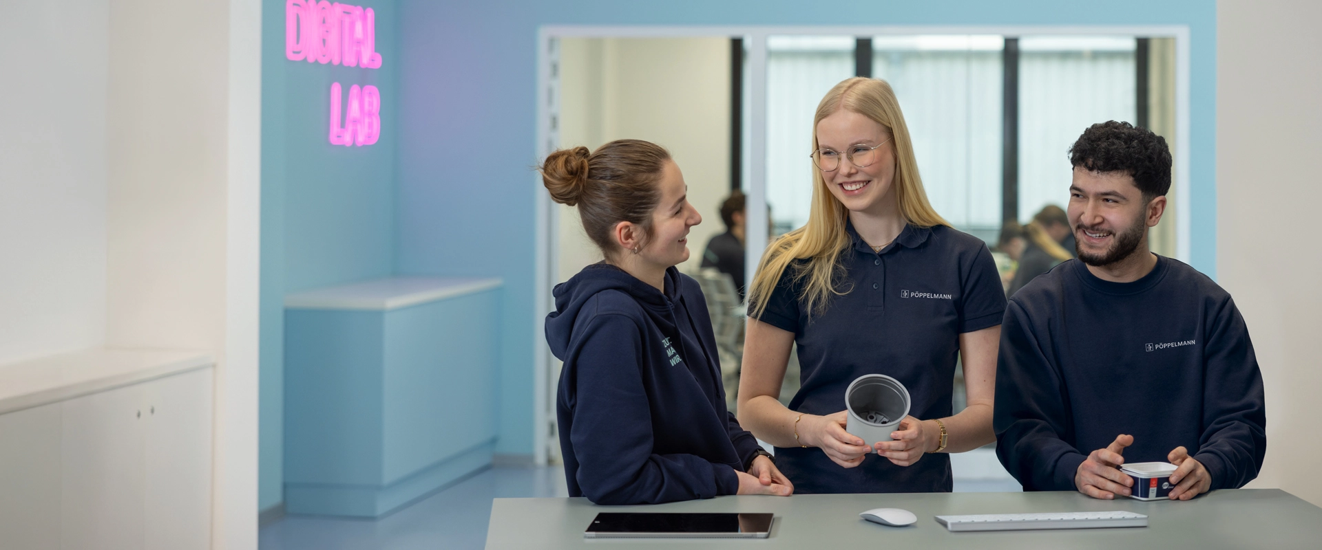 Drei Auszubildende von Pöppelmann unterhalten sich über ein Projekt und haben Spaß an ihrer Arbeit